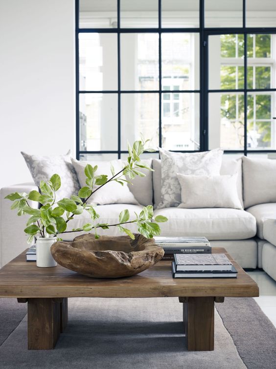 _ a-modern-rustic-coffee-table-with-a-rough-wooden-bowl-books-and-a-greenery-arrangement-in-a-vase