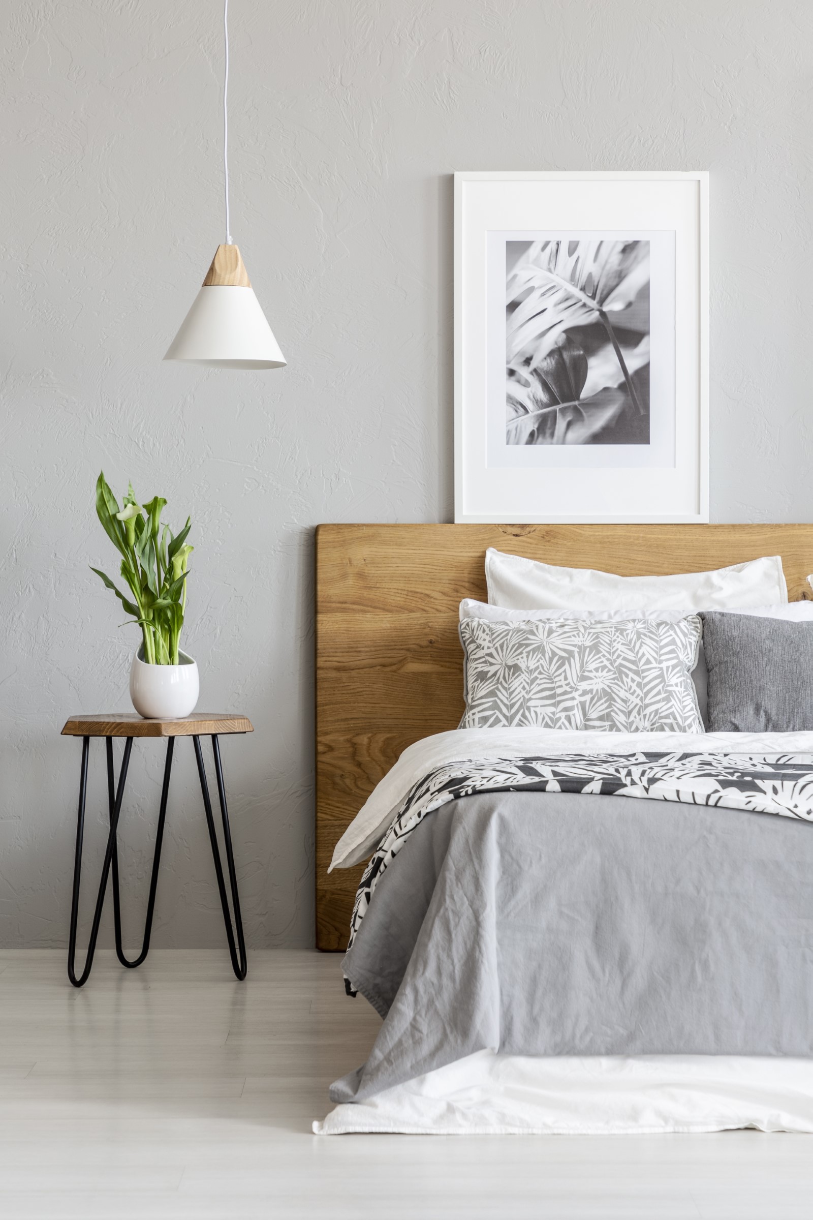 plant-on-table-next-to-wooden-bed-in-grey-bedroom-QB7WPCA.jpg